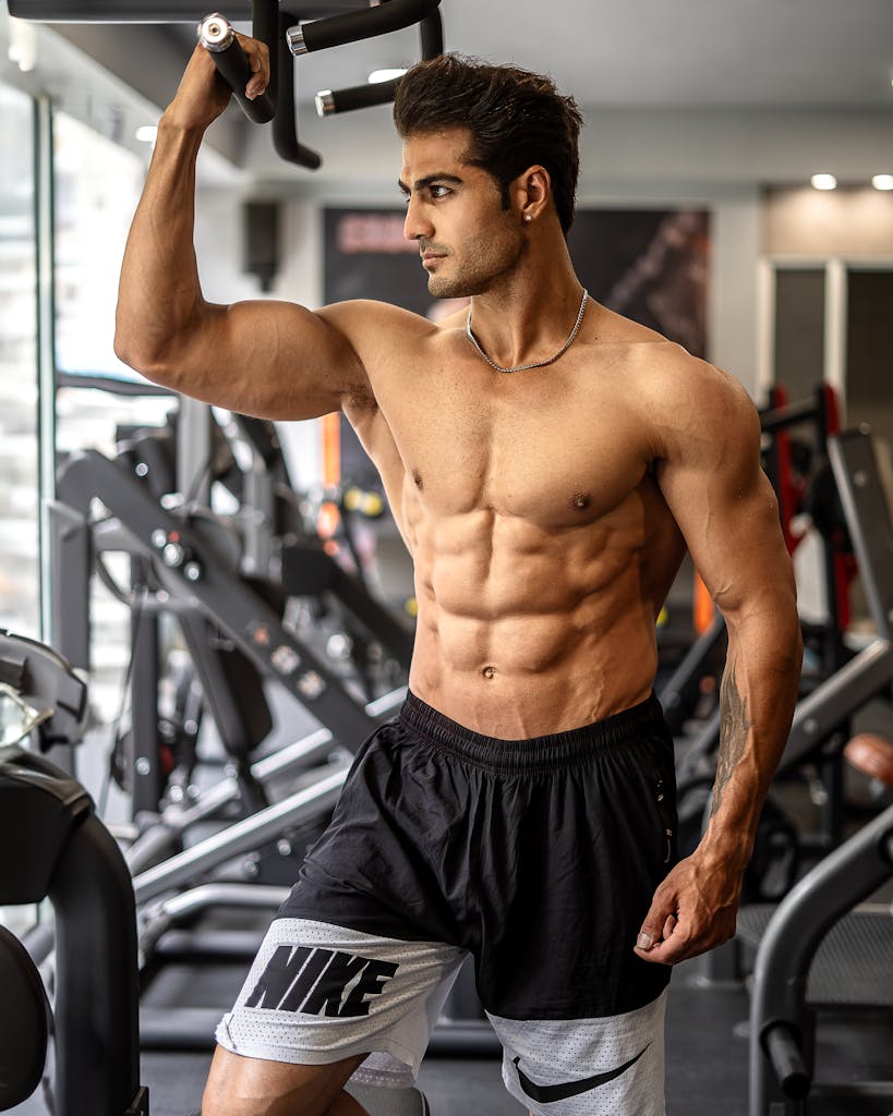 Young Muscular Man Standing Shirtless at the Gym after taking performance enhancing supplements